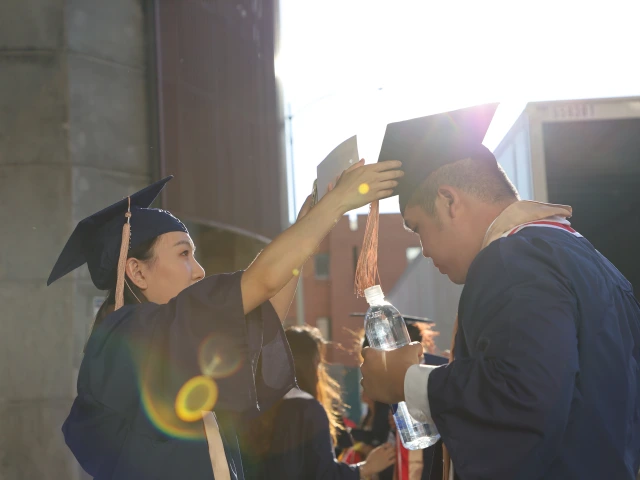 One student helps another with their graduation cap.