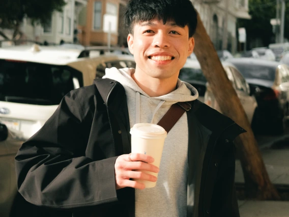 Man holding coffee cup on busy San Francisco street.
