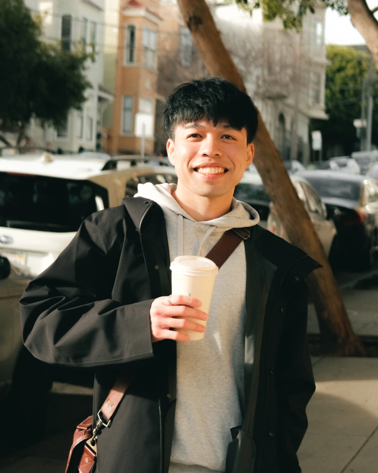 Man holding coffee cup on busy San Francisco street.